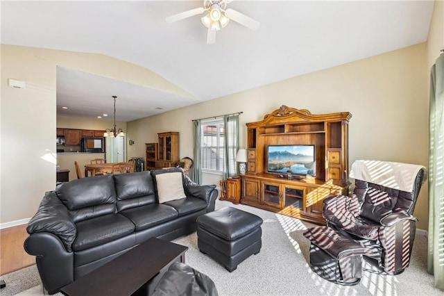 living room with lofted ceiling and ceiling fan with notable chandelier