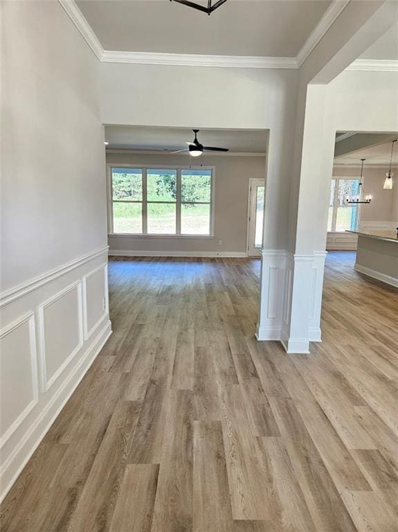 spare room featuring a wealth of natural light, wainscoting, light wood-style flooring, and crown molding