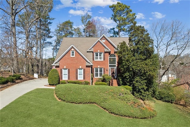 traditional-style home with brick siding and a front lawn