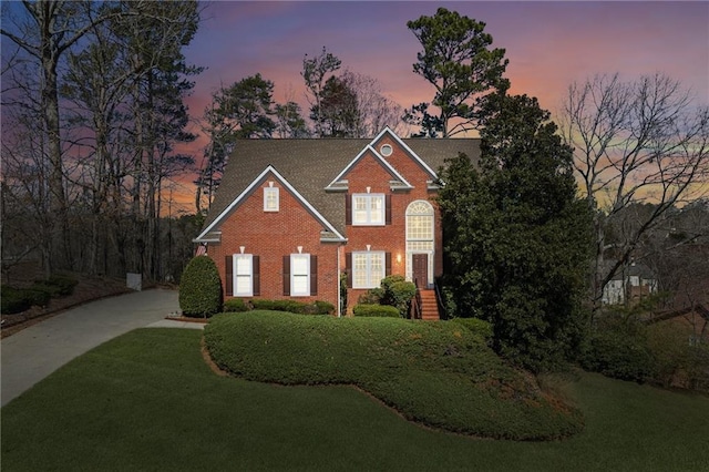 view of front of home with a yard and brick siding