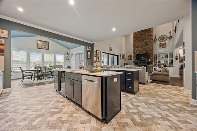 kitchen with a kitchen island with sink, light countertops, open floor plan, baseboards, and vaulted ceiling