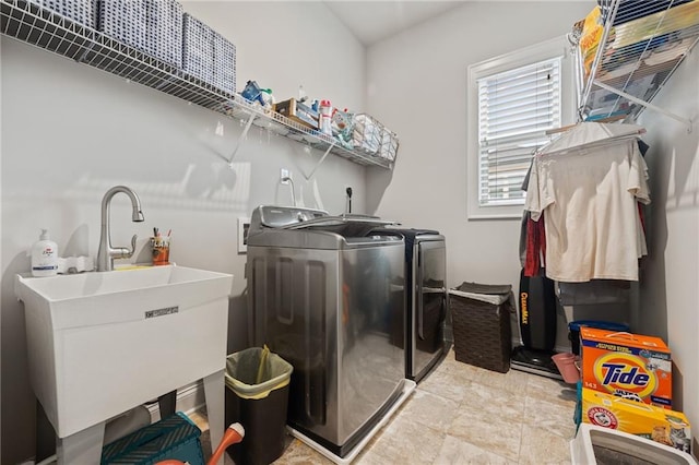 laundry room featuring stone finish flooring, laundry area, a sink, and washer and clothes dryer