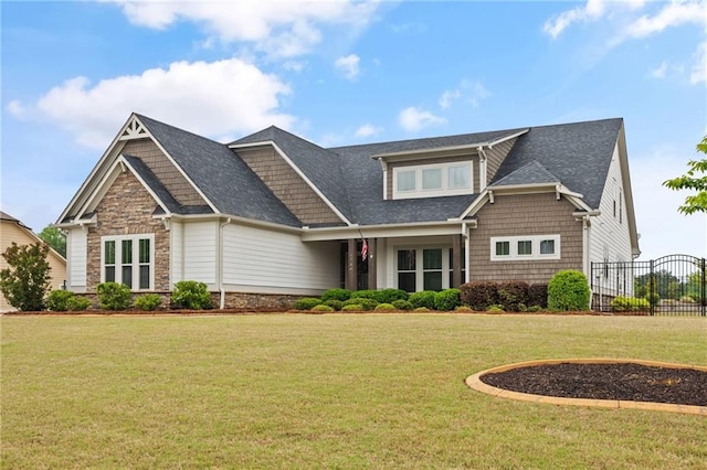 craftsman inspired home with a front lawn, roof with shingles, fence, and stone siding