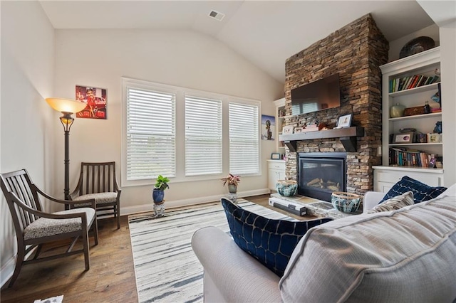 living room featuring visible vents, lofted ceiling, a fireplace, baseboards, and hardwood / wood-style flooring
