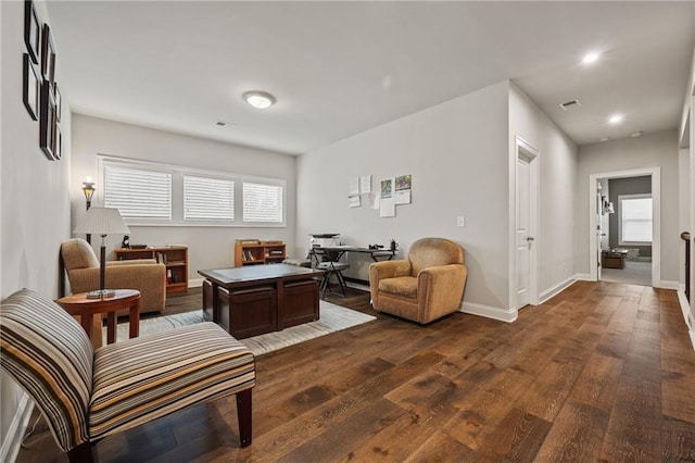 living area featuring baseboards, visible vents, dark wood-style floors, and a wealth of natural light