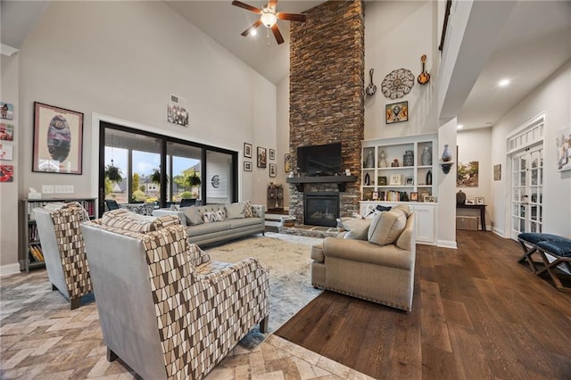living area featuring a fireplace, high vaulted ceiling, a ceiling fan, baseboards, and wood finished floors