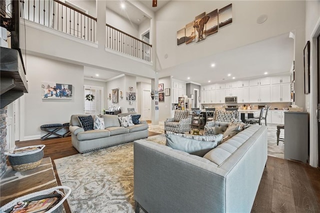 living area featuring recessed lighting, baseboards, a high ceiling, and dark wood-style flooring