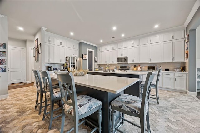kitchen with a sink, white cabinets, stainless steel appliances, and a kitchen bar