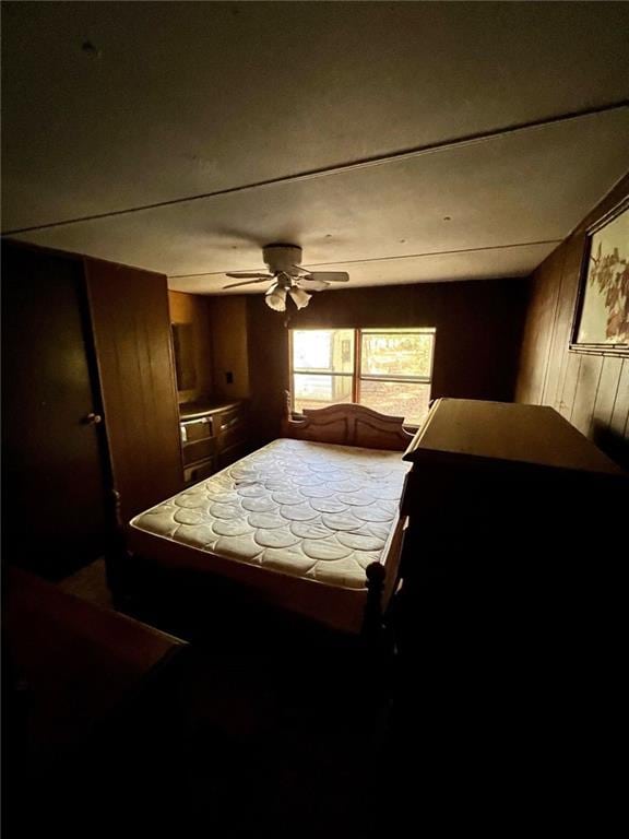 bedroom with wooden walls and ceiling fan