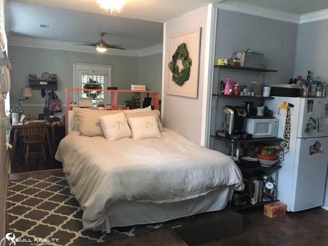 bedroom with ceiling fan, dark hardwood / wood-style flooring, white fridge, and ornamental molding