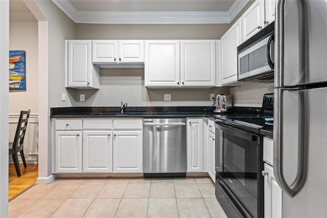 kitchen featuring appliances with stainless steel finishes, ornamental molding, white cabinetry, a sink, and light tile patterned floors