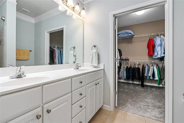 bathroom featuring tile patterned flooring, crown molding, double vanity, and a walk in closet