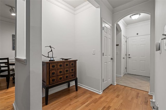 hall with arched walkways, light wood-type flooring, crown molding, and baseboards