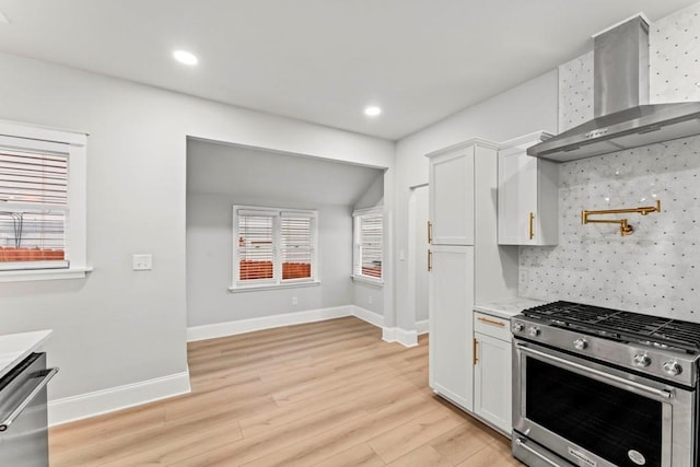 2128 Hosea L Williams Dr NE, Atlanta, GA 30317 - kitchen featuring appliances with stainless steel finishes, wall chimney exhaust hood, light wood-style flooring, light countertops, and white cabinets