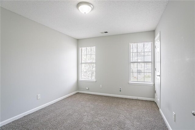 carpeted empty room with baseboards, a textured ceiling, and visible vents