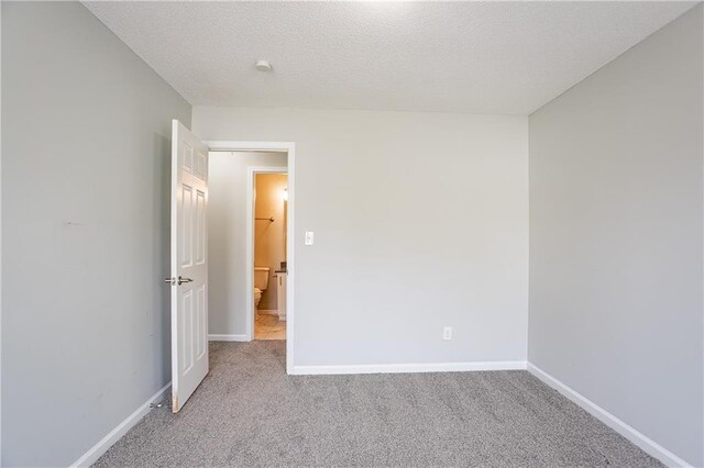 empty room with baseboards, a textured ceiling, and light colored carpet