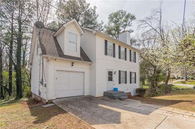 colonial home with driveway, a garage, roof with shingles, and a chimney