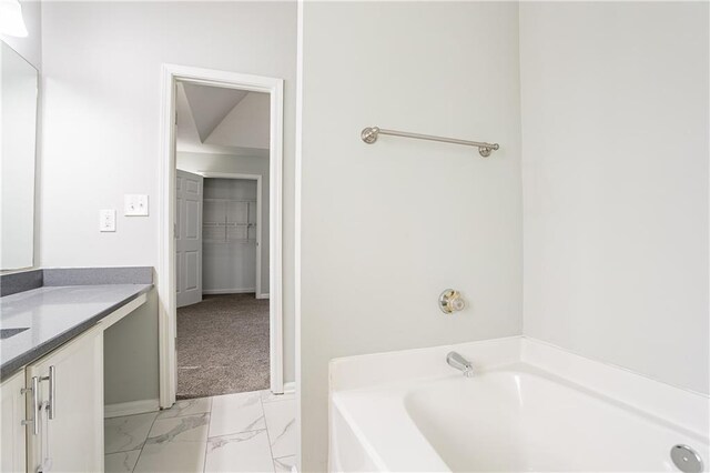 full bathroom with marble finish floor, a bath, and vanity