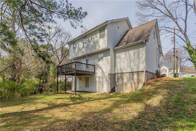 rear view of house featuring a lawn and a wooden deck
