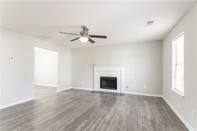 unfurnished living room featuring visible vents, a textured ceiling, wood finished floors, and a ceiling fan