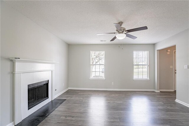 unfurnished living room featuring a fireplace with flush hearth, a textured ceiling, visible vents, ceiling fan, and dark wood-style flooring