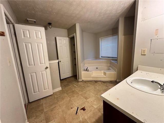 bathroom featuring a tub to relax in, vanity, and a textured ceiling