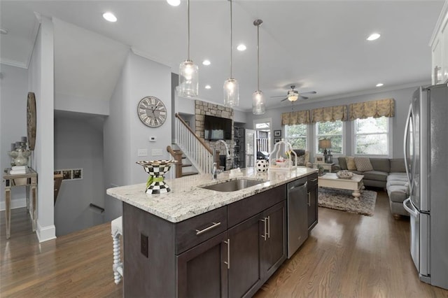 kitchen with sink, dark brown cabinets, appliances with stainless steel finishes, dark hardwood / wood-style floors, and an island with sink