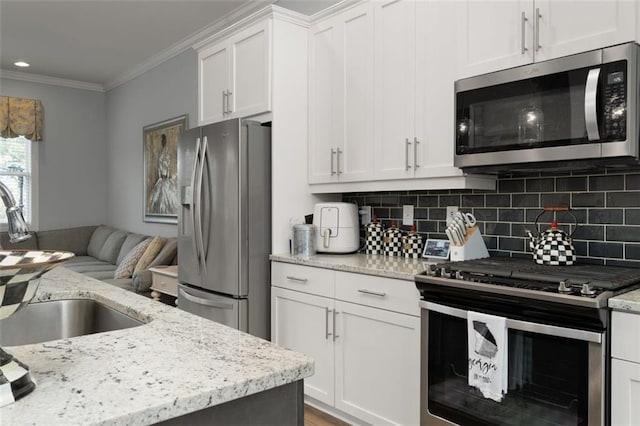 kitchen featuring sink, crown molding, white cabinetry, backsplash, and stainless steel appliances