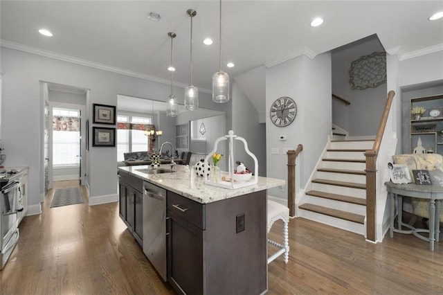 kitchen with sink, hanging light fixtures, dark brown cabinetry, stainless steel appliances, and a center island with sink