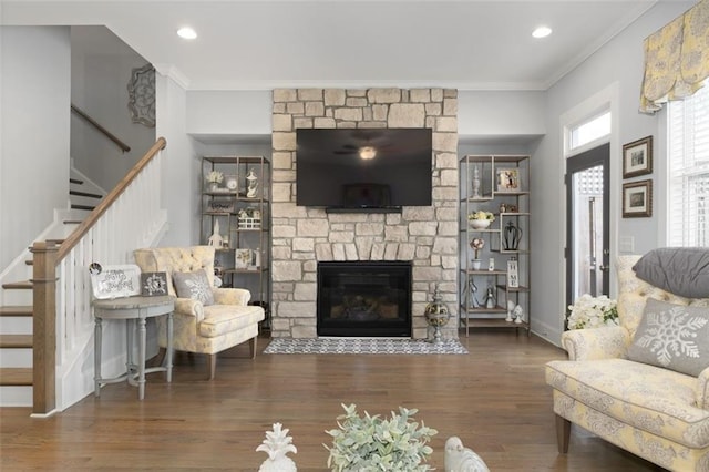 living room with ornamental molding, dark hardwood / wood-style floors, and a stone fireplace