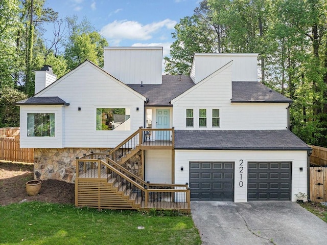 rear view of house featuring aphalt driveway, fence, stairway, and a garage