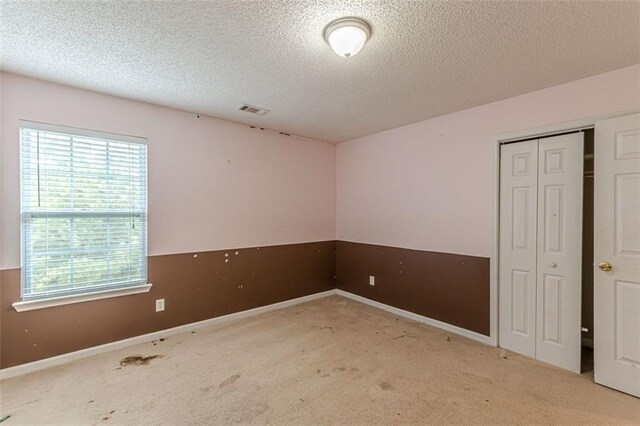 carpeted spare room with a textured ceiling