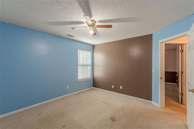 unfurnished room featuring ceiling fan, light colored carpet, and a textured ceiling