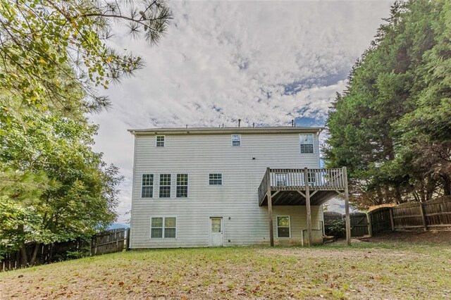 rear view of house with a lawn and a wooden deck