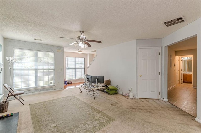 interior space featuring light carpet, a textured ceiling, and ceiling fan