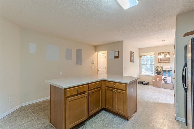 kitchen featuring a chandelier, stainless steel fridge, a kitchen island, and hanging light fixtures