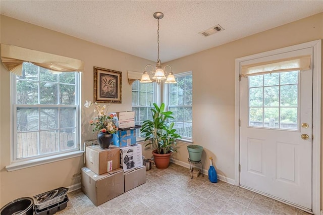 interior space with a textured ceiling, an inviting chandelier, and a wealth of natural light