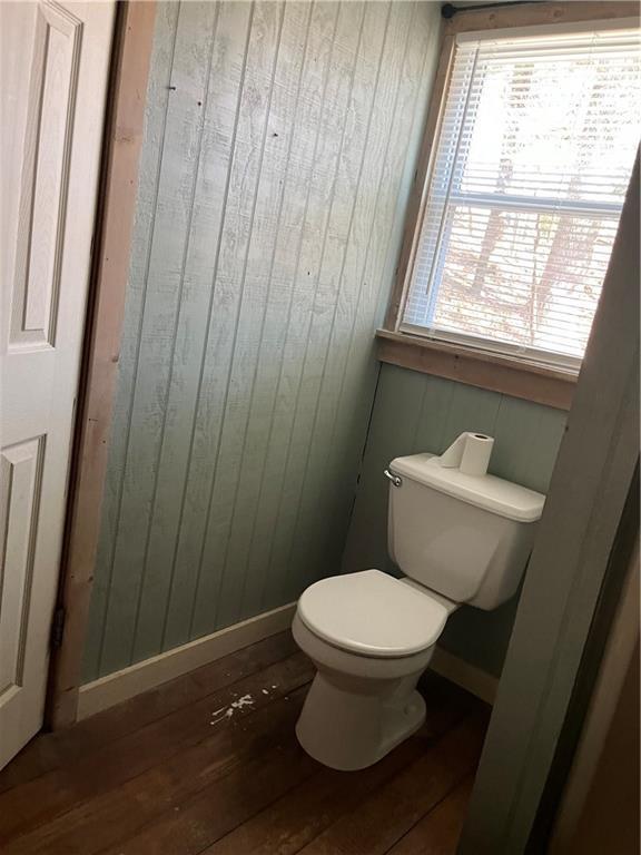 bathroom with hardwood / wood-style flooring, toilet, and wood walls