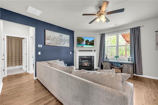 509 Azalea Bloom Dr, Loganville, GA 30052 - living room featuring ceiling fan, visible vents, baseboards, a glass covered fireplace, and light wood-style flooring