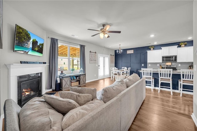 509 Azalea Bloom Dr, Loganville, GA 30052 - living room featuring recessed lighting, a ceiling fan, a glass covered fireplace, and light wood-type flooring