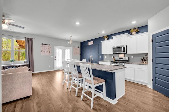 509 Azalea Bloom Dr, Loganville, GA 30052 - kitchen featuring a sink, a breakfast bar area, light wood-style flooring, stainless steel appliances, and open floor plan