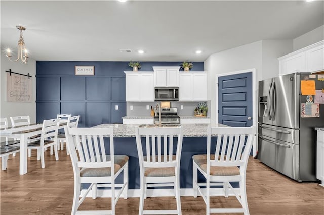 509 Azalea Bloom Dr, Loganville, GA 30052 - kitchen featuring a center island with sink, a barn door, white cabinets, a sink, and appliances with stainless steel finishes