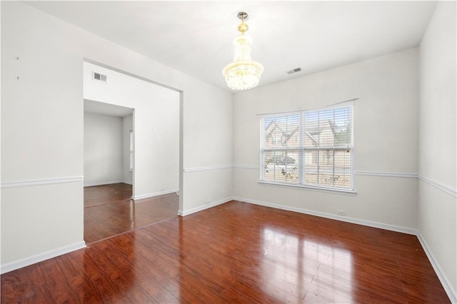 empty room featuring dark hardwood / wood-style flooring and a notable chandelier