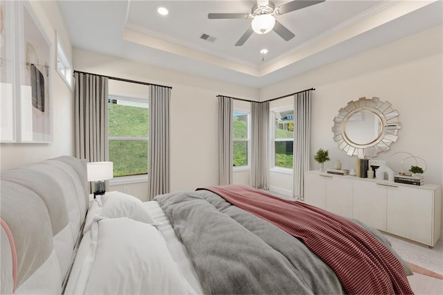 bedroom featuring multiple windows, visible vents, a raised ceiling, and light colored carpet