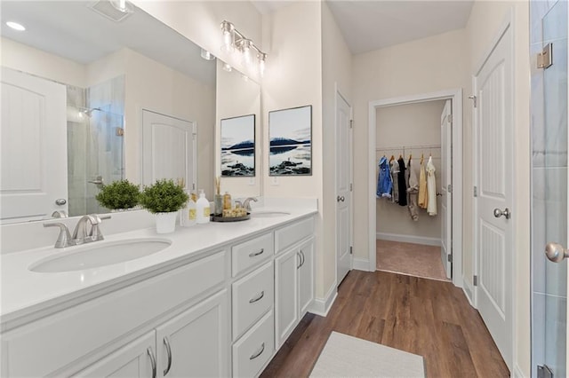 full bath featuring a stall shower, wood finished floors, a sink, and double vanity