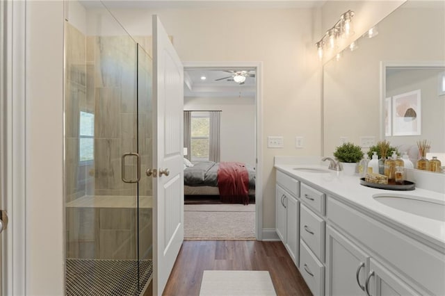 ensuite bathroom with a sink, a shower stall, ensuite bath, and wood finished floors