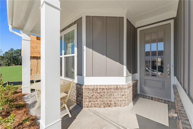 view of exterior entry featuring a porch and board and batten siding