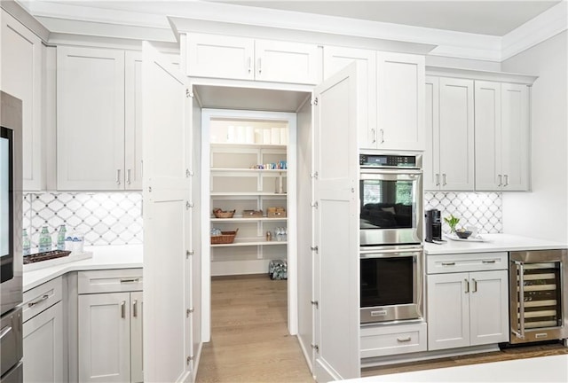 4025 Connolly Ct, Roswell, GA 30075 - kitchen with wine cooler, stainless steel double oven, light countertops, backsplash, and light wood-type flooring