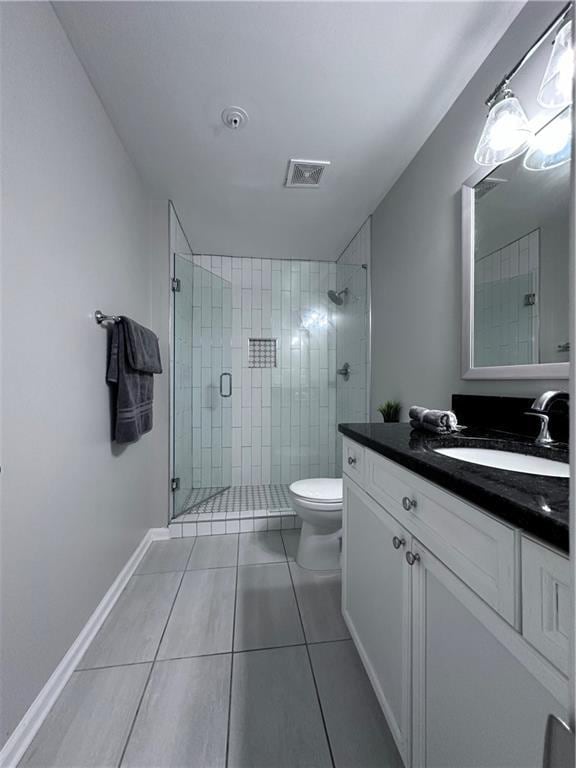 bathroom featuring vanity, toilet, an enclosed shower, and tile patterned flooring