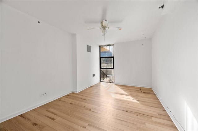 spare room with ceiling fan, light wood-type flooring, and floor to ceiling windows